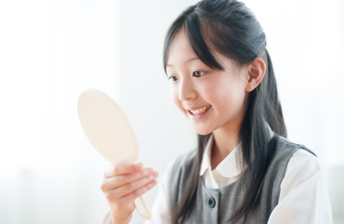 鏡で歯並びを確認する女の子